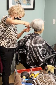 Photo of Kathleen Parker giving a resident a hair cut.