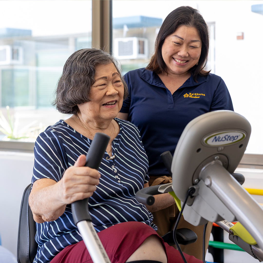 services Kalakaua staff smiling and standing next to a client on a recumbent bicycle
