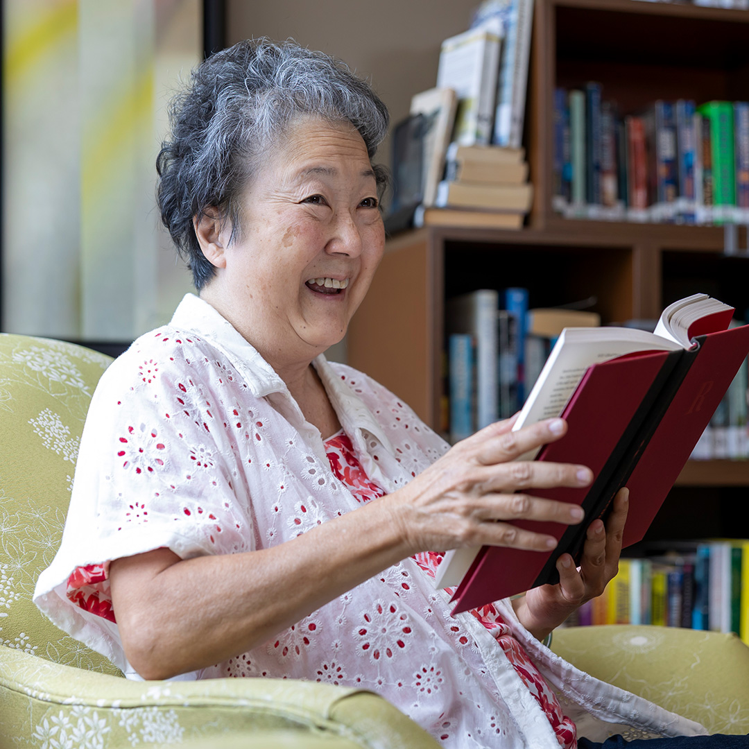 testimonial Woman smiling holding a book.
